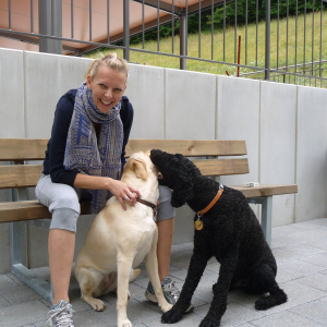 Lia Stoll a light-skinned woman with blond hair and her two guide dogs. 
